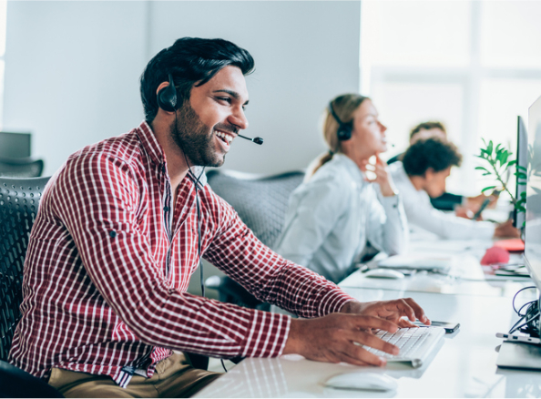 Man in a plaid shirt using a headset to provide customer service via the phone